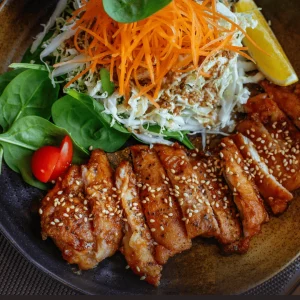 A plate of Indian-style chicken, garnished with vibrant spices, served alongside a fresh salad featuring mixed greens, tomatoes and carrots.