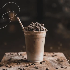 A cup of freshly brewed coffee placed on a surface surrounded by scattered coffee beans, creating a warm and inviting atmosphere